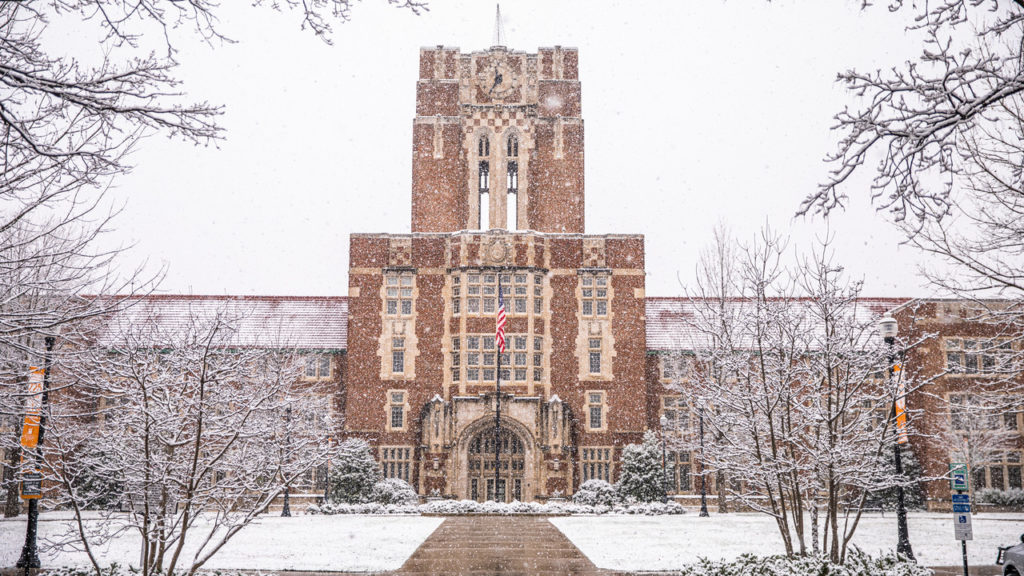 Ayres Hall during a snowfall with snow covering all of the trees and grass.